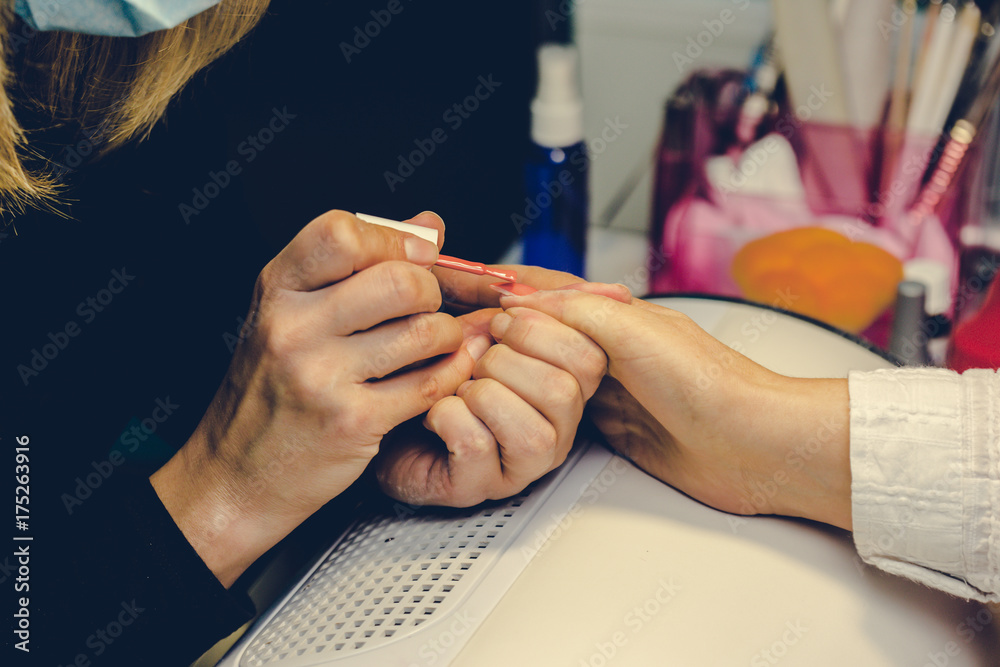 Girl paint nails in the salon of manicure, close-up