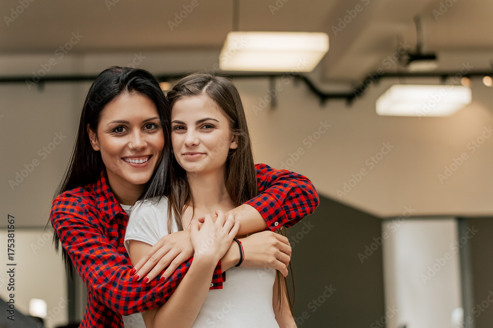 两个漂亮女孩在室内拥抱的特写肖像。