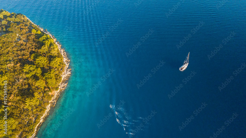 Aerial view of sailing boat anchoring next to reef