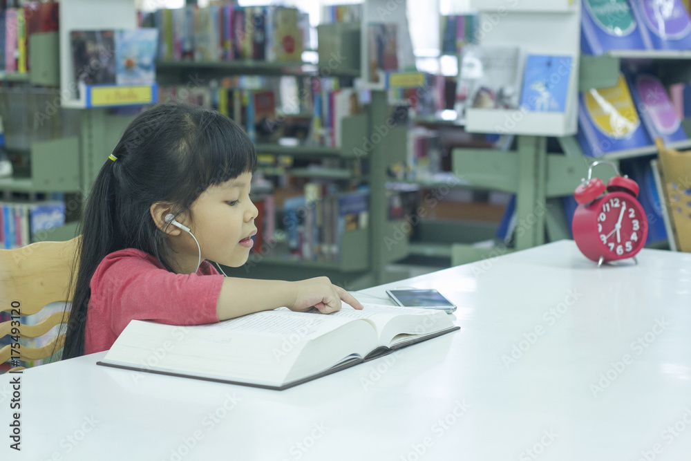 little asia girl intend to reading book at library