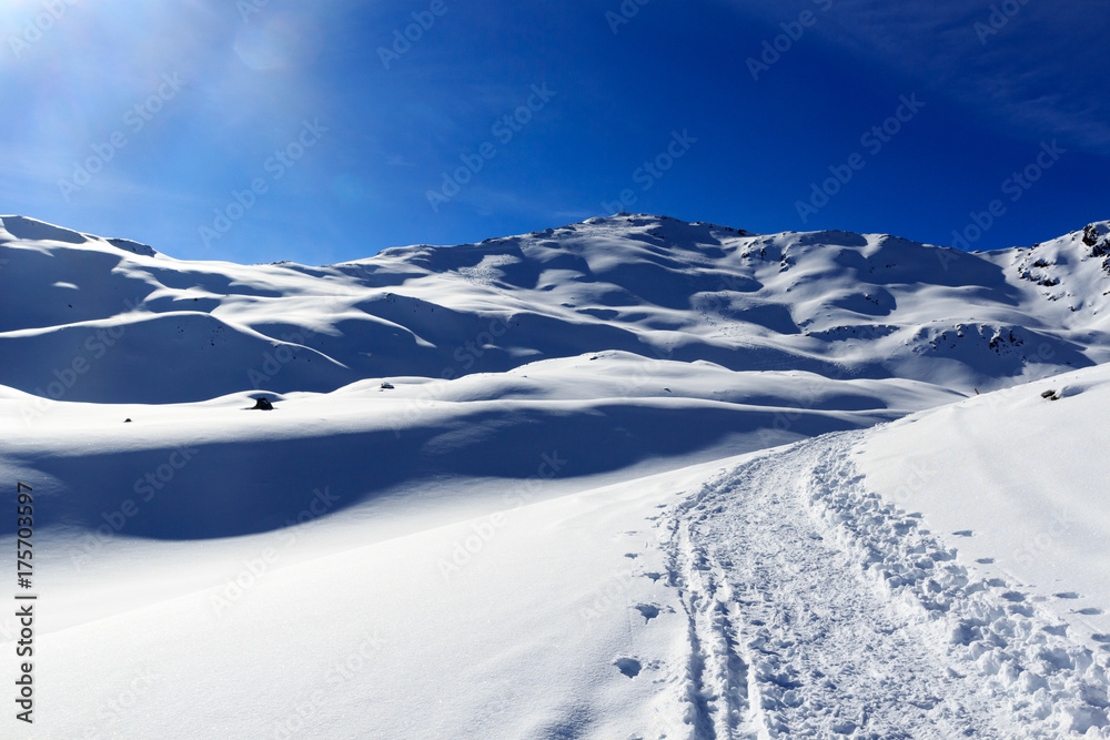 Mountain panorama with snow, sun and snowshoe trail in winter in Stubai Alps, Austria