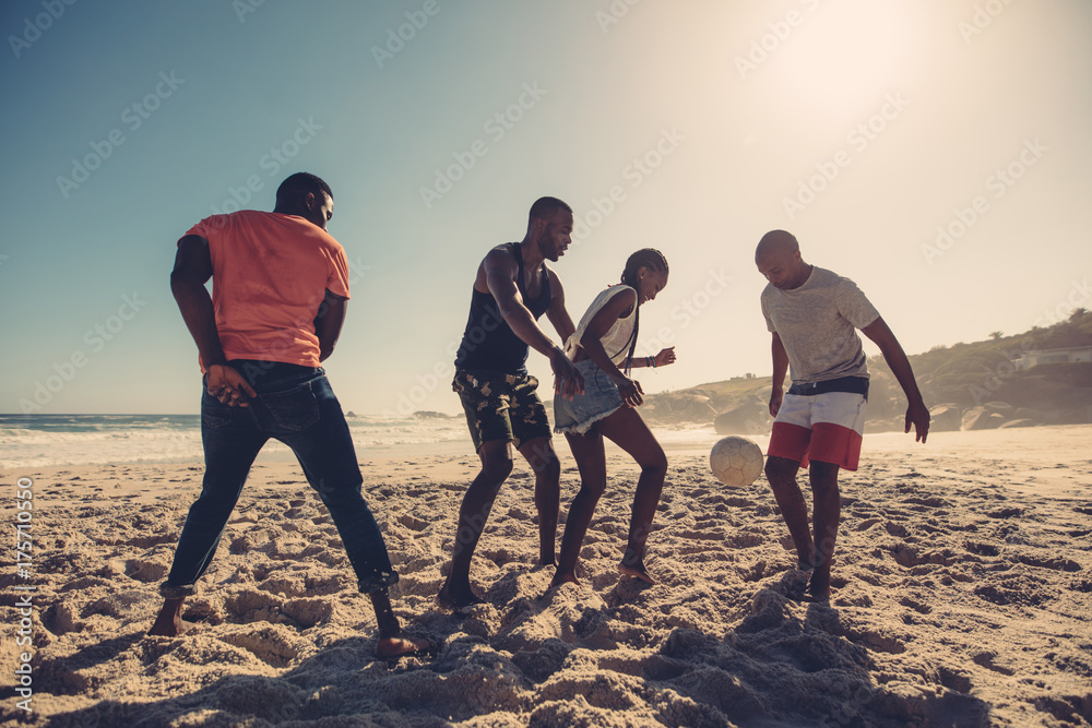 Friends enjoying a game of soccer at beach