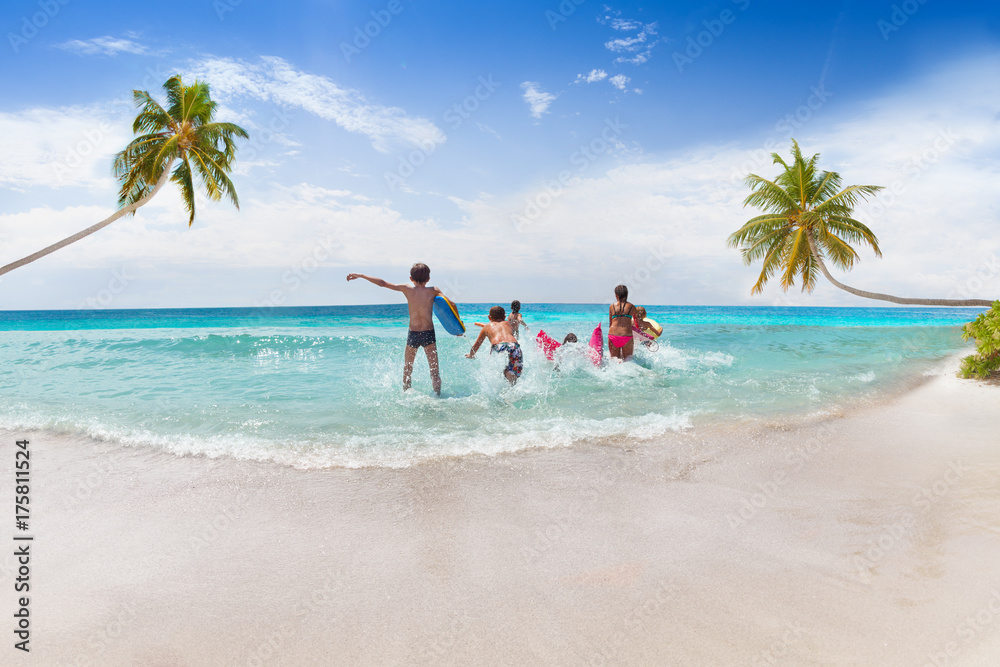 Group of kinds running into the sea on sand beach