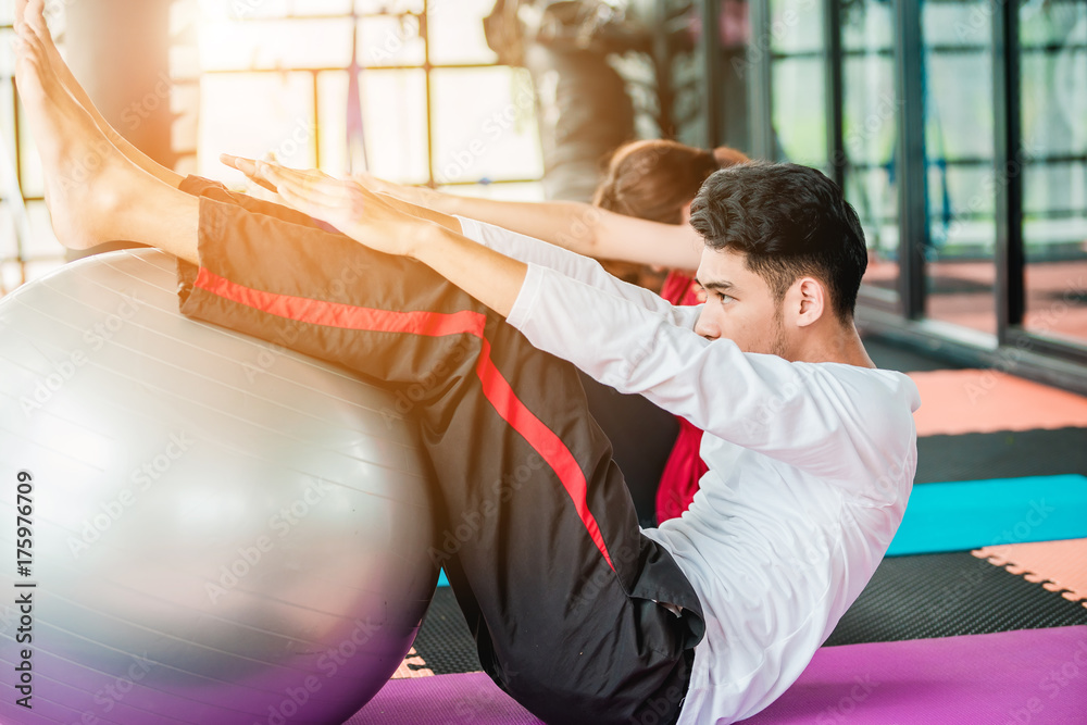 Asian teenage girl exercises with a fitness ball in the fitness center with happiness.