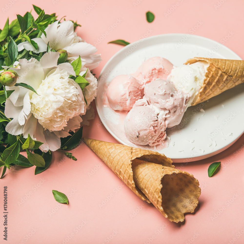 Flatlay of pastel pink strawberry and coconut ice cream scoops, sweet cones on white plate and white