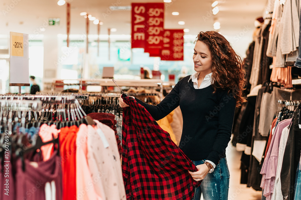 在店里挑选基本服装的深色女性顾客。