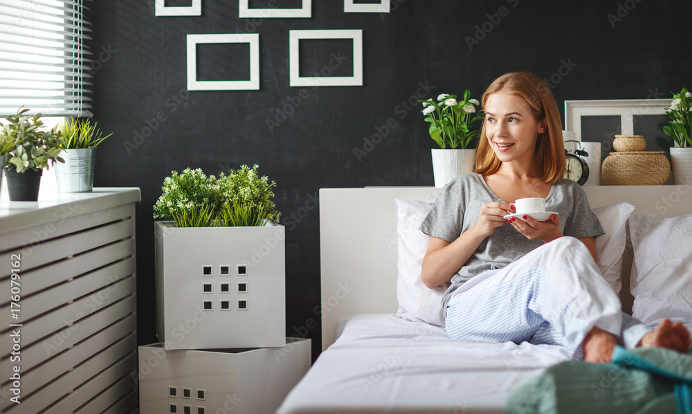 happy young woman with cup of morning coffee in bed