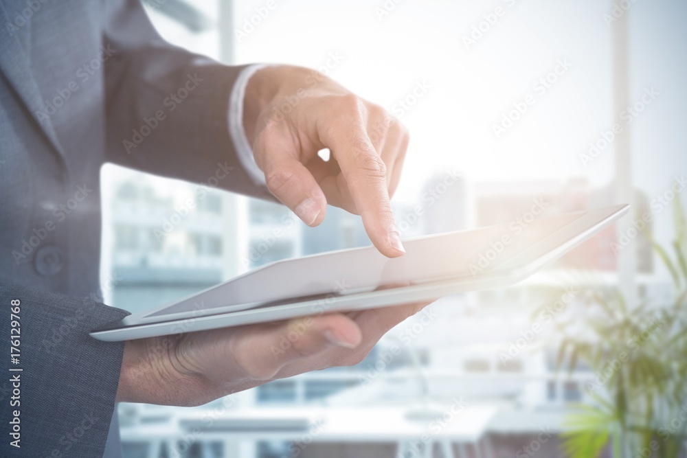 Composite image of mid section of businessman using tablet