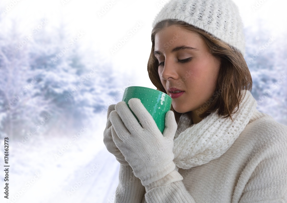 戴着手套和帽子的女人在雪地里用杯子喝水