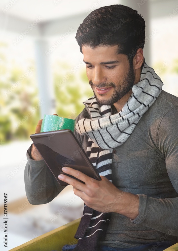 Man in Autumn with tablet and cup and scarf at home