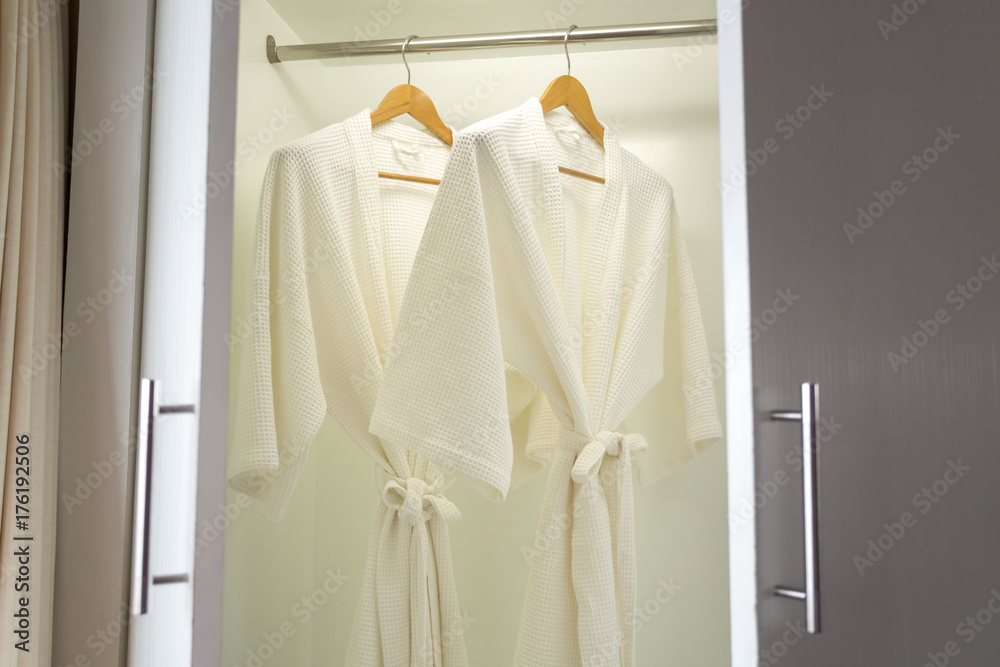 two off white color bathrobes hanging in closet, room for copy space