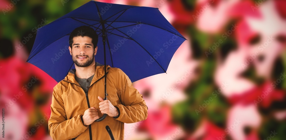 Composite image of portrait of young man holding blue umbrella