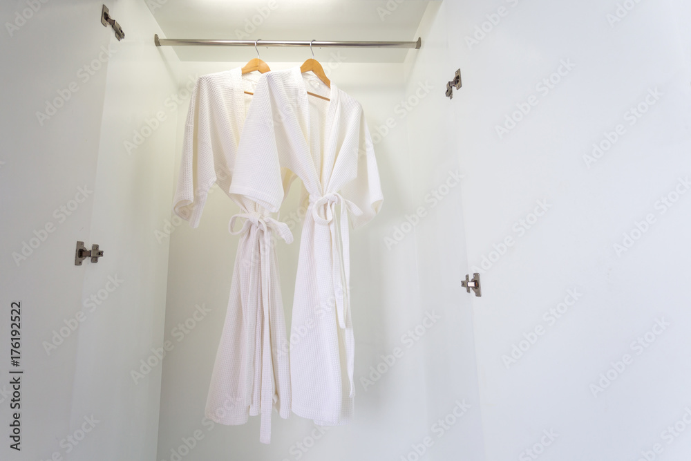 two off white color bathrobes hanging in closet, room for copy space