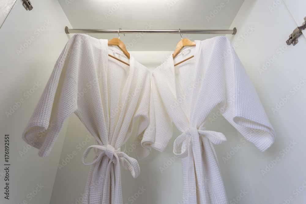 two off white color bathrobes hanging in closet, room for copy space