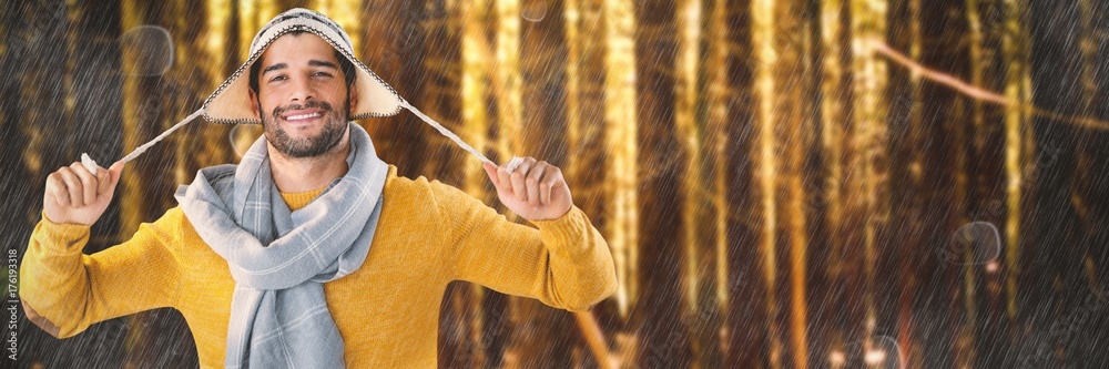 Composite image of portrait of smiling man holding wooly hat