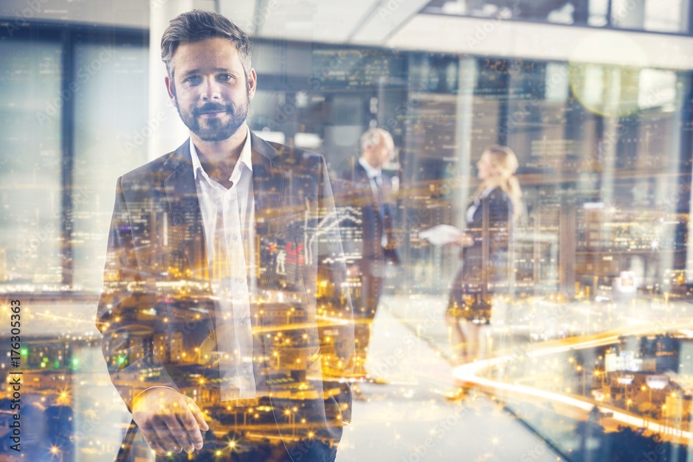 Businessman standing in office corridor and colleagues talking