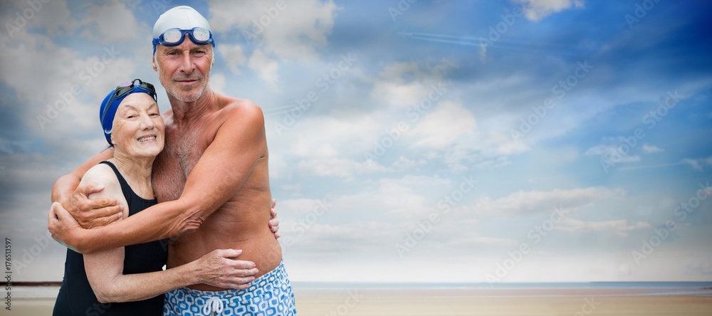 Composite image of smiling senior couple in swimwear embracing