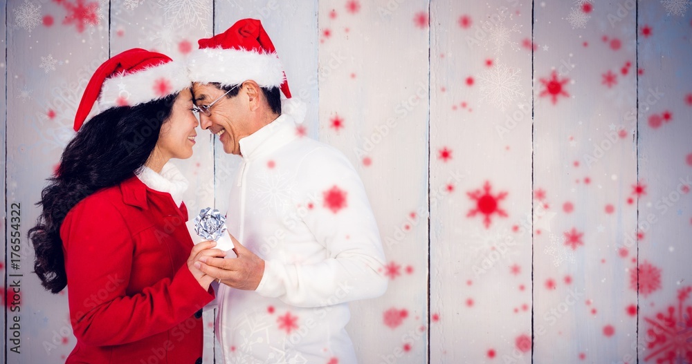 Composite image of festive senior couple exchanging gifts