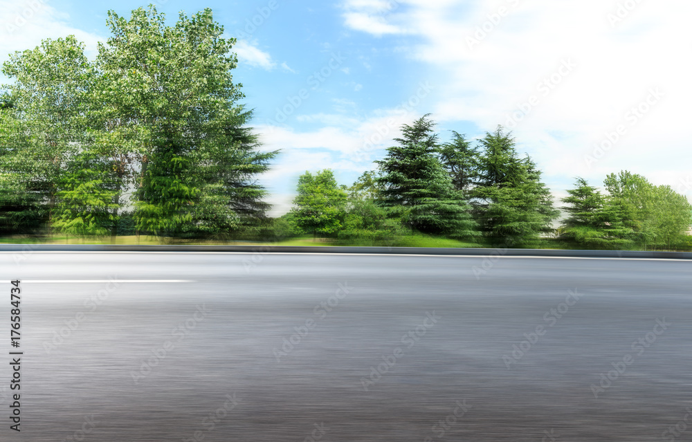 Motion blur asphalt road and forest under the blue sky