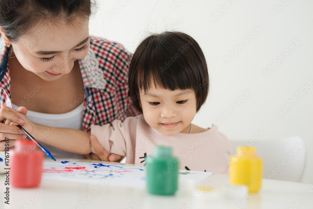 Mother looking how her child daughter drawing a picture