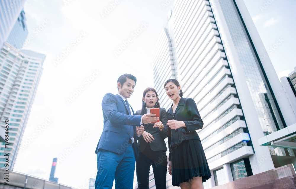 Surprised business people using smart phone outdoors . excited young businessman and business woman 