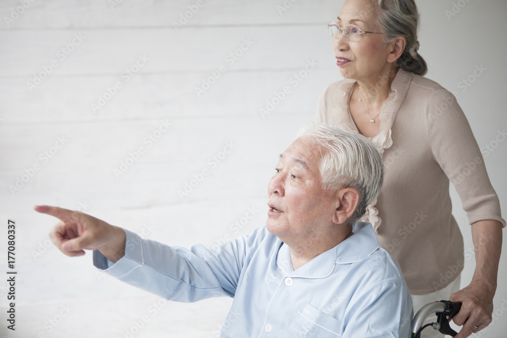 A husband who points to a window with a woman who pushes a wheelchair