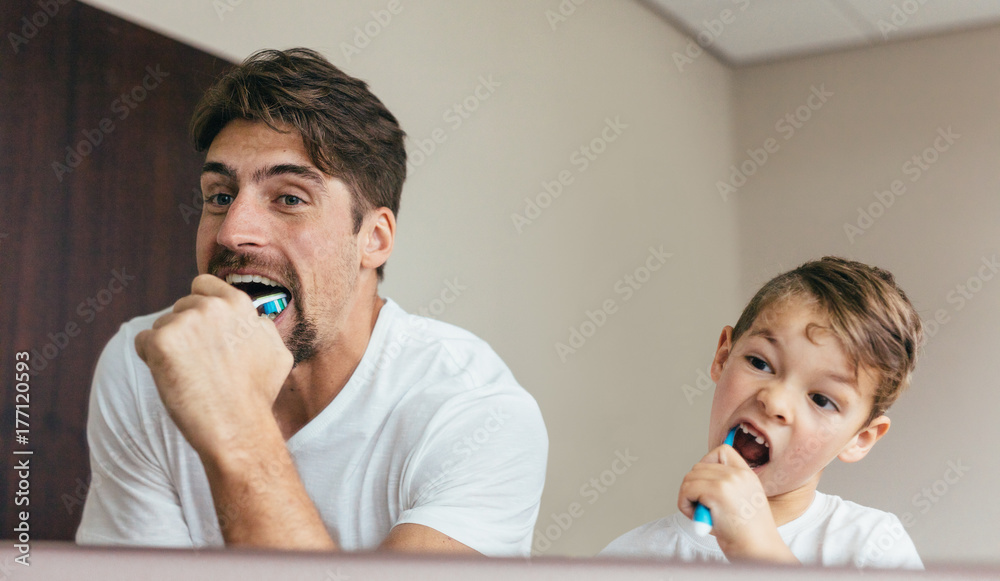 Father and son brushing teeth in bathroom