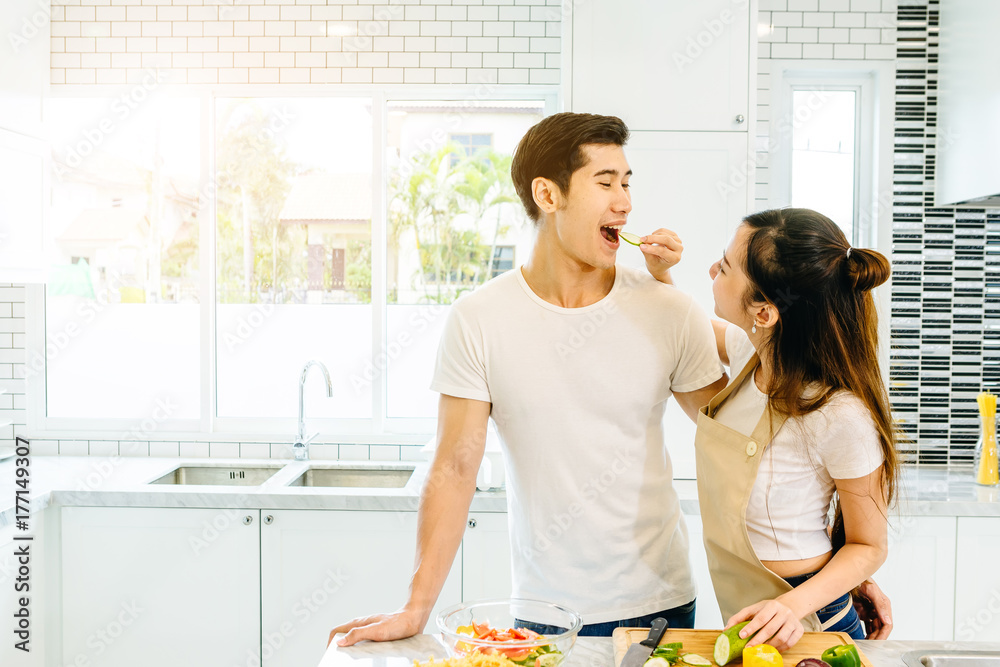 一对亚洲青少年夫妇正在帮忙做晚饭。他们一起快乐地做面包。在美国的情人节