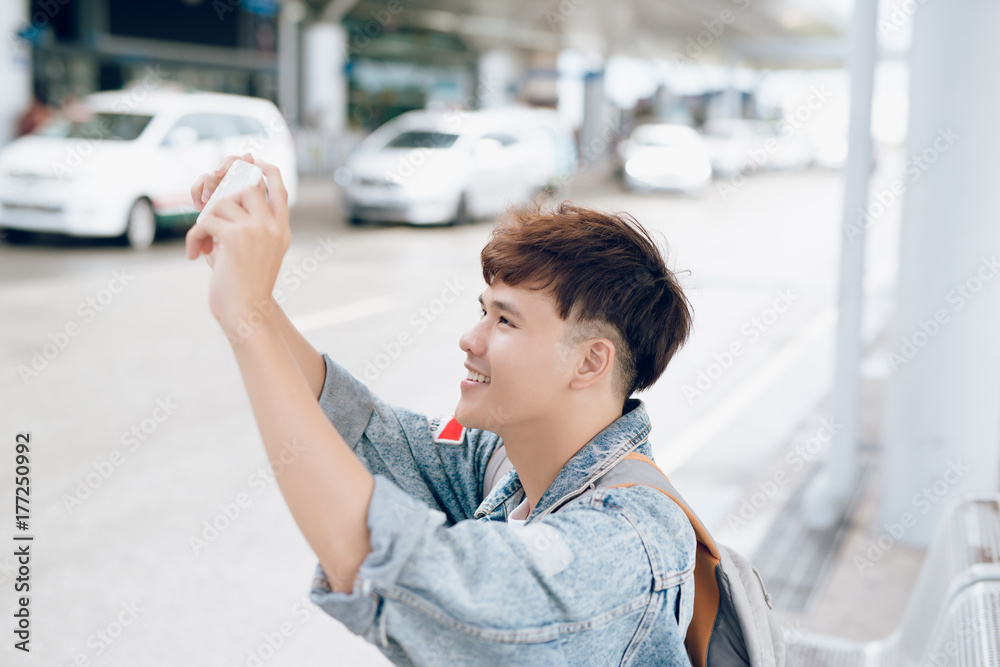 亚洲男性旅客在机场等出租车时拍照