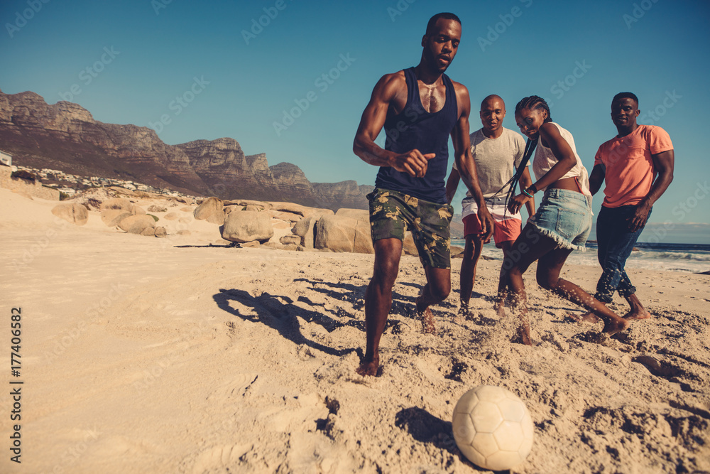 Friends playing soccer on the beach