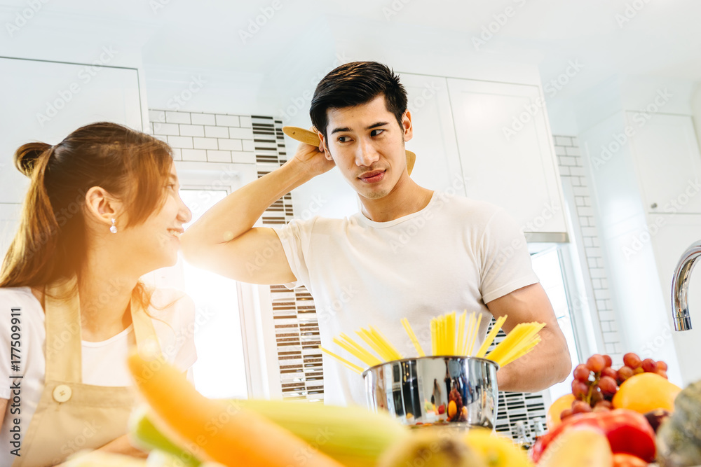 一对亚洲青少年夫妇正在帮忙做晚饭。他们一起快乐地做面包。在美国的情人节