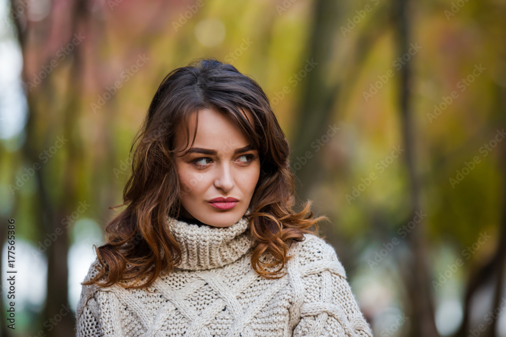 Beautiful emotional woman in an autumn park, looking away.