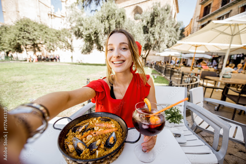 身穿红色连衣裙的年轻女子与传统巴伦西亚米饭sea Paella和S自拍