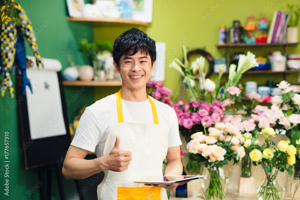 亚洲男性花商在花店柜台做笔记的裁剪图