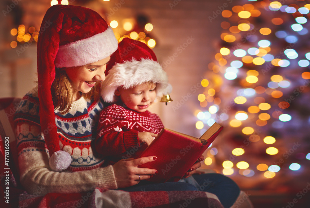 Christmas Eve. family mother and baby reading magic book at home .