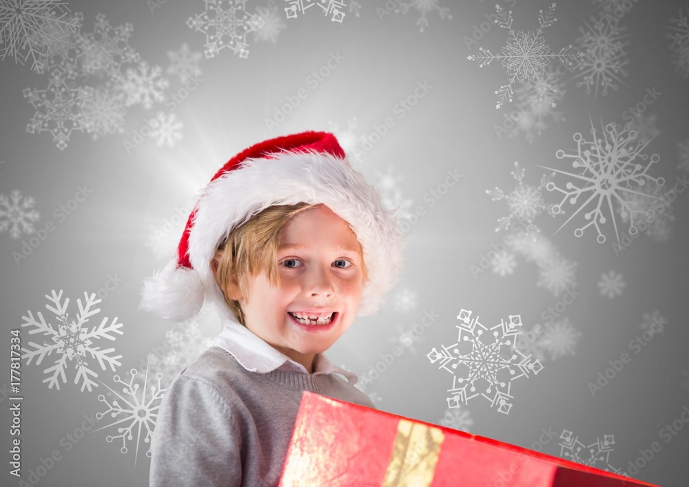 Boy against grey background with gift and Santa Christmas hat