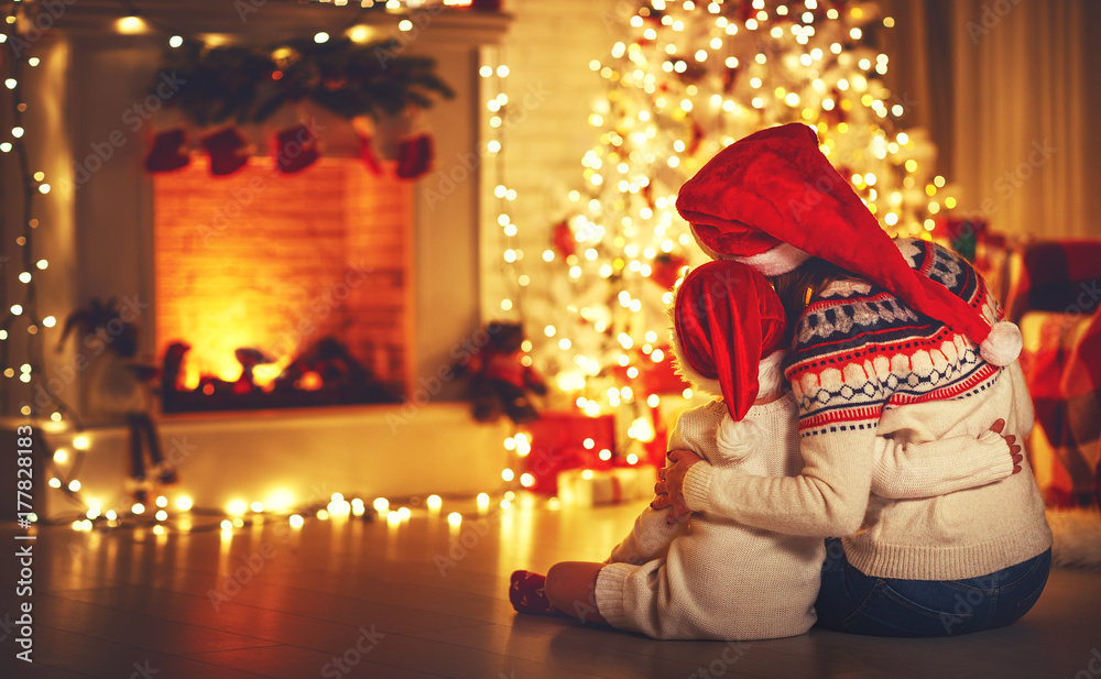 happy family mother and daughter sitting  backs near tree on of Christmas.