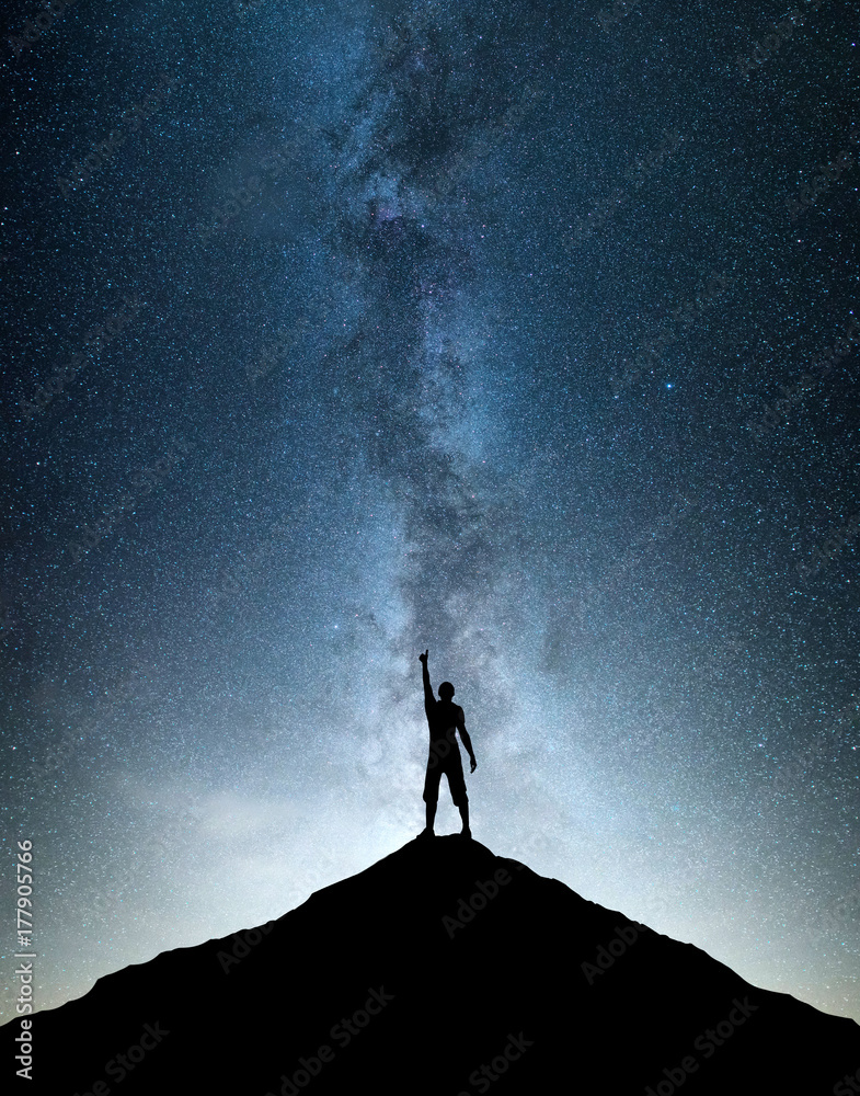 山峰上胜利者的剪影。夜空背景下的运动和积极的生活理念。