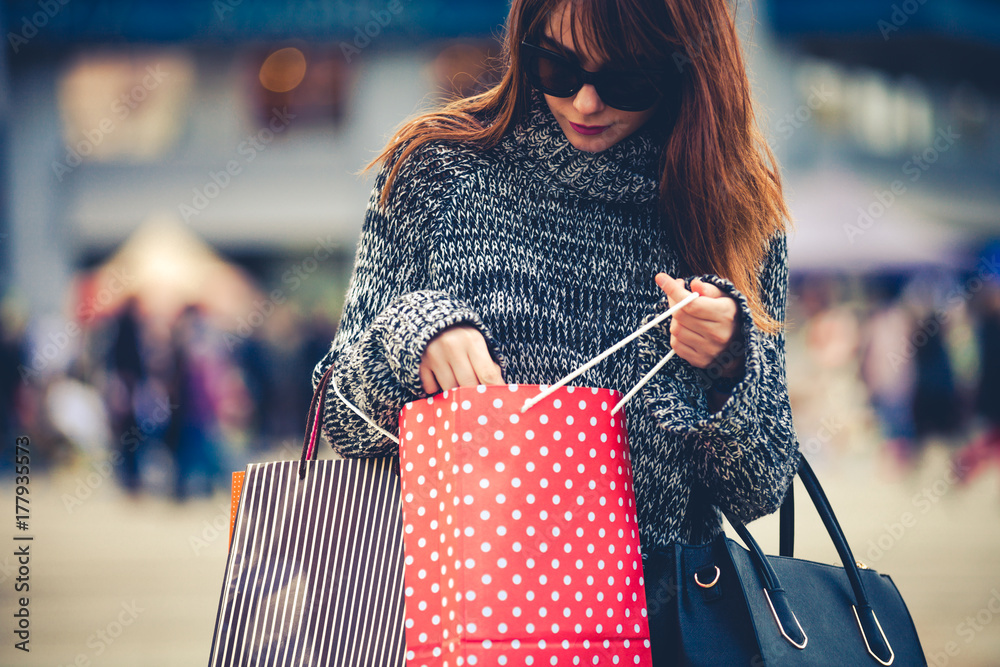 Pretty woman at the city street looking into shopping bag