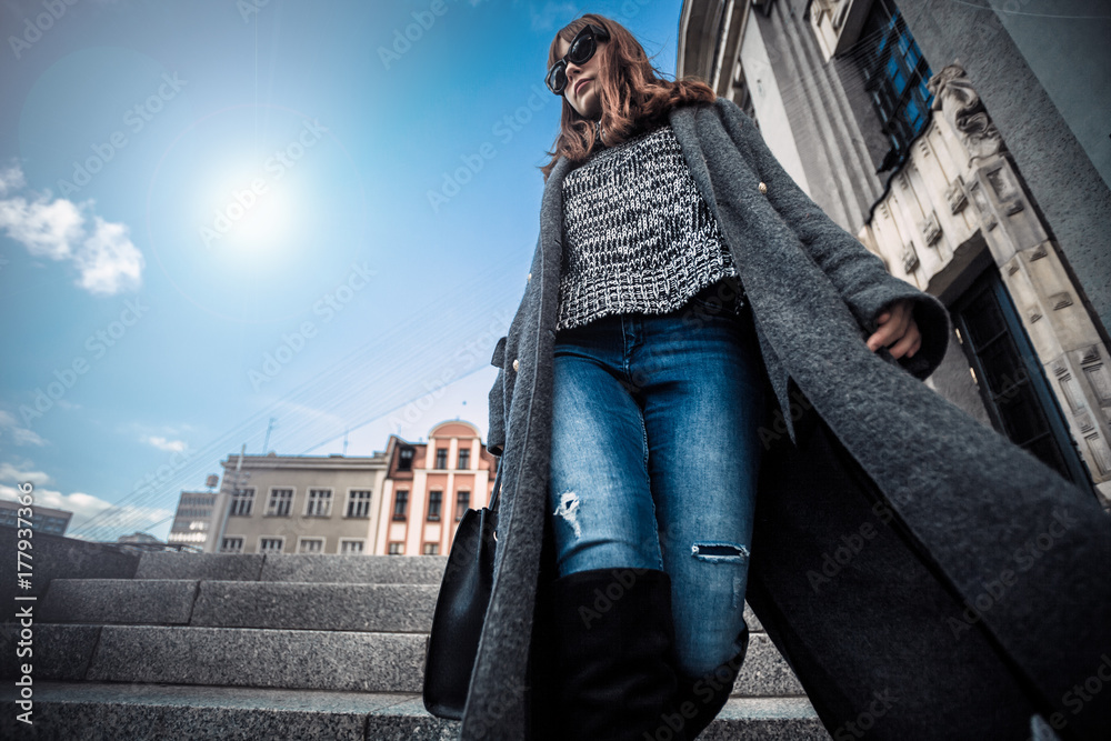 休闲时尚都市场景，穿着外套的时髦女人走在街上