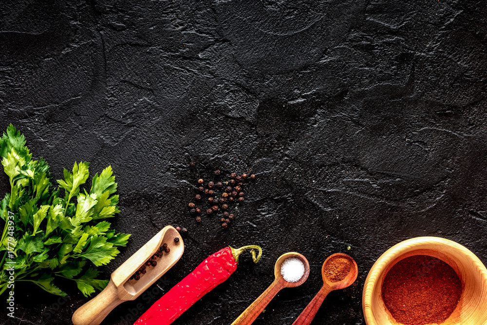 spices in wooden spoon on dark background top view