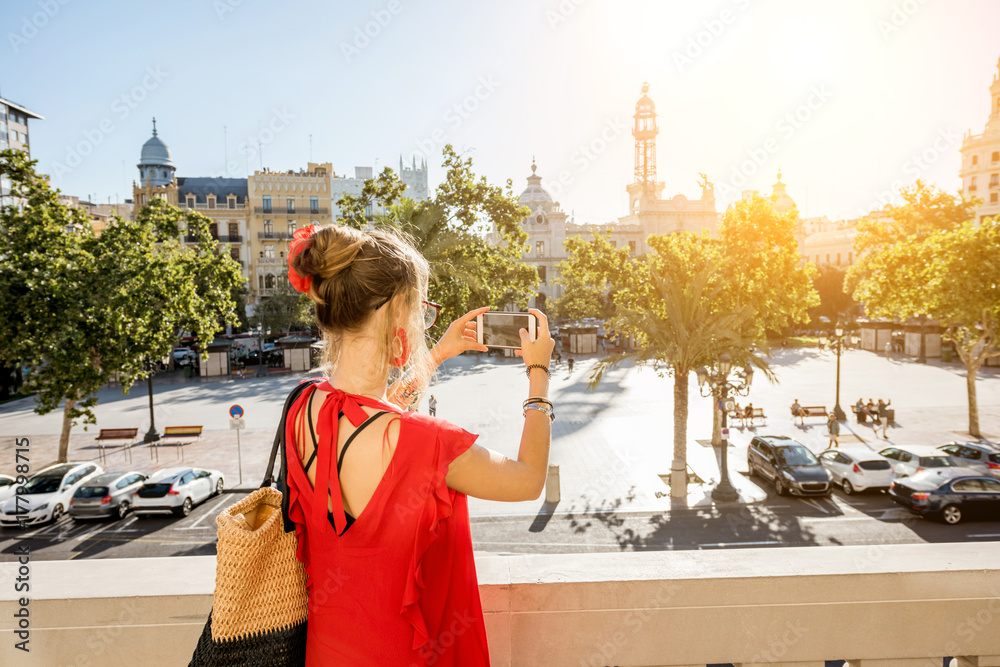 身穿红色连衣裙的年轻女游客在市政厅大楼的露台上拍摄Ayuntamiento广场