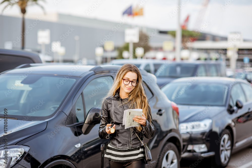 Young woman looking on the rental contract standing outdoors on the airport car parking