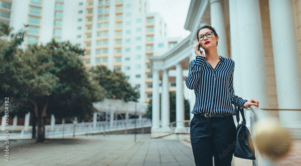 女商人用手机在户外行走