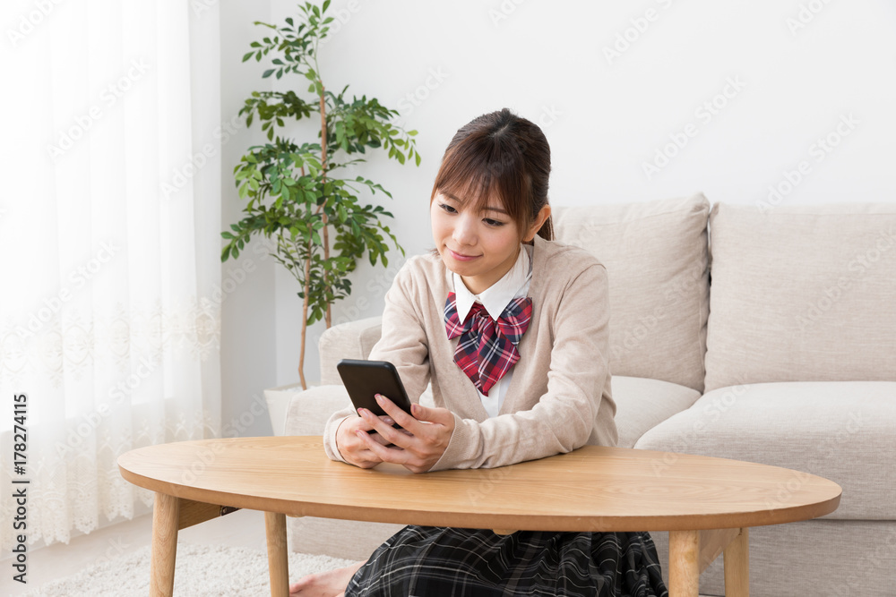 リビングでスマートフォンを使う女子高生