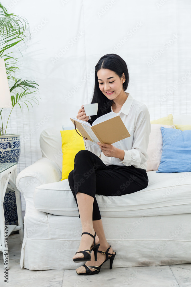 beautiful asian woman sit relax reading book with tea or coffee white room interior