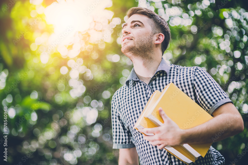 white man student happiness smiling with yellow book in the garden