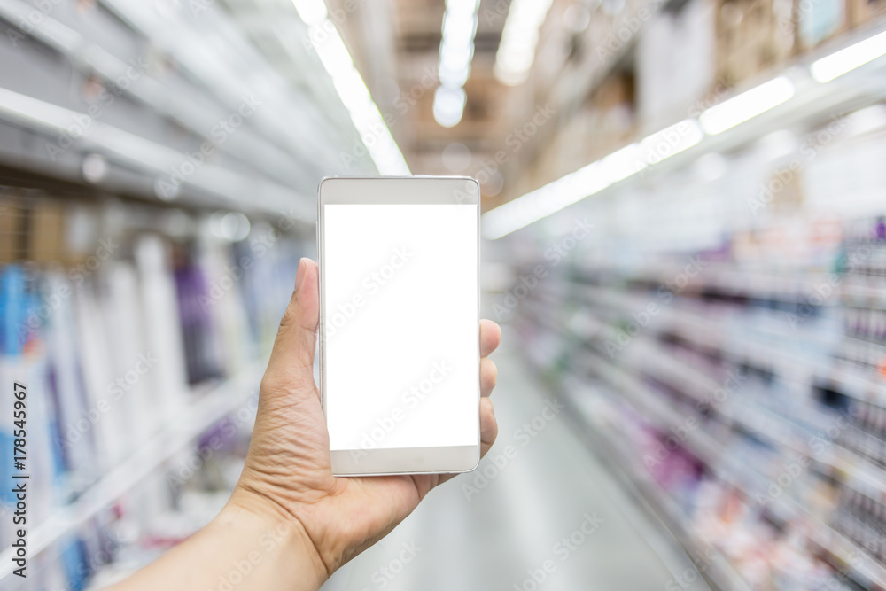 hand with smartphone with blur background image of shopping mall or department store with bokeh and 