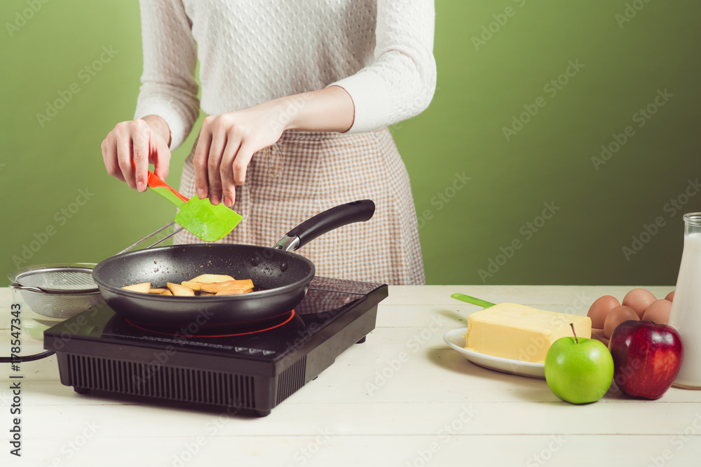 穿着围裙的家庭主妇制作。烹饪苹果蛋糕的步骤。切青苹果。