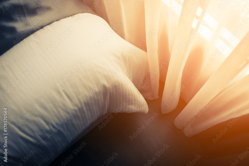 Bed maid-up with clean white pillows and bed sheets in beauty room. Close-up. Lens flair in sunlight